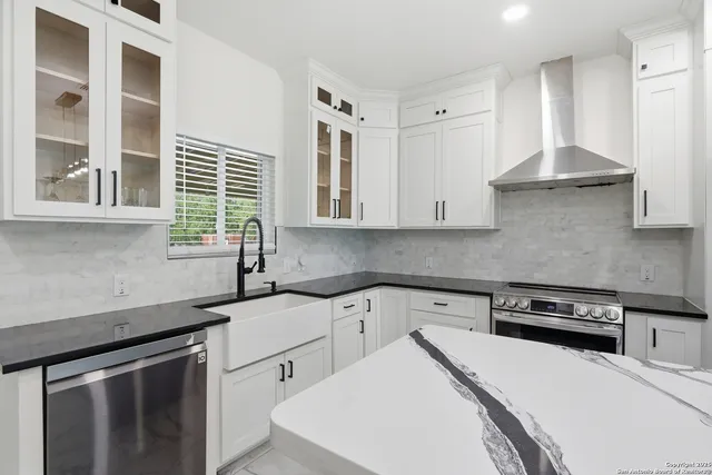 a kitchen with stainless steel appliances a sink a stove and white cabinets