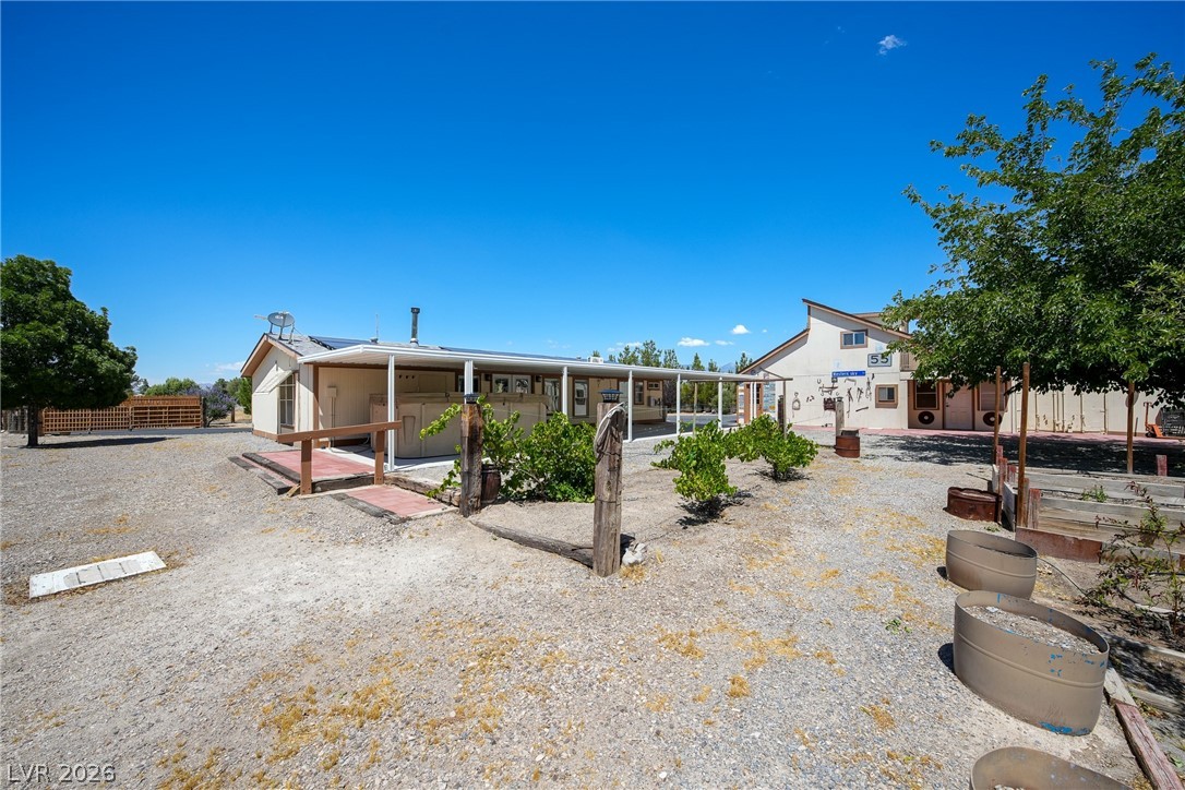 1831 West Horn Road Pahrump, NV 89048 - Photo 34 of 59 A spacious gravel lot with multiple structures and ample outdoor space under a clear sky.
