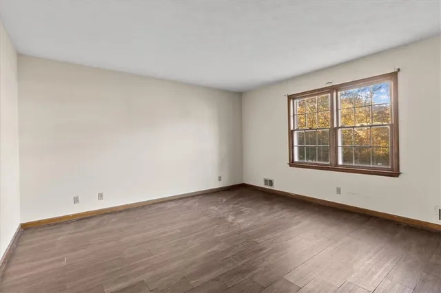 an empty room with wooden floor and mirror