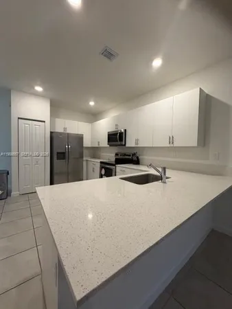 a large kitchen with stainless steel appliances a refrigerator sink and microwave