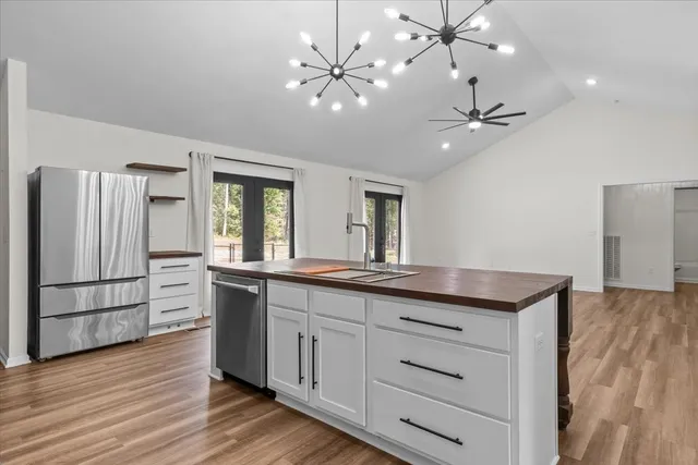 a kitchen with stainless steel appliances granite countertop a refrigerator a sink and white cabinets