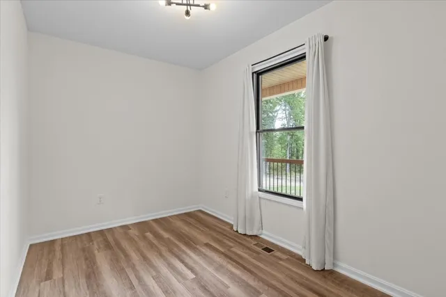 a view of an empty room with closet and wooden floor