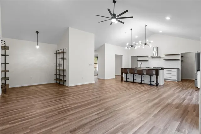 an empty room with wooden floor furniture and a chandelier