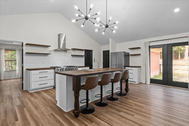 a kitchen with stainless steel appliances a dining table chairs and wooden floor