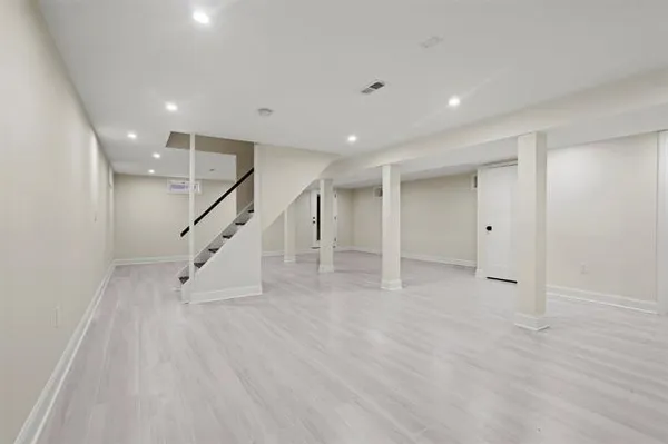 a view of an empty room with wooden floor and stairs