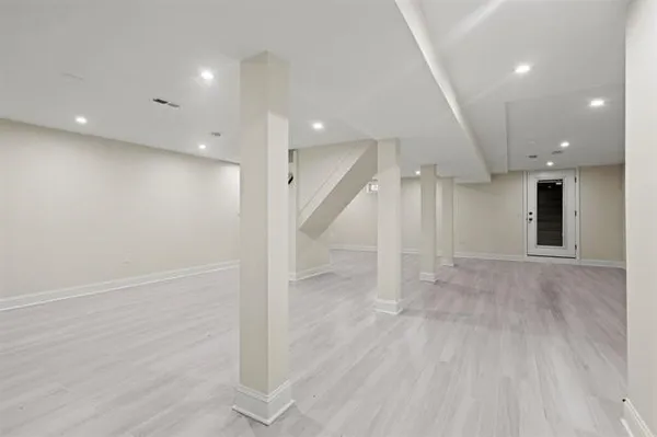 an empty room with wooden floor and a kitchen