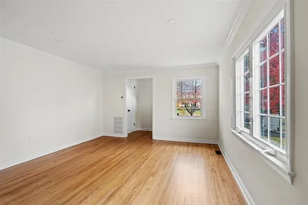 a view of an empty room with wooden floor and a window