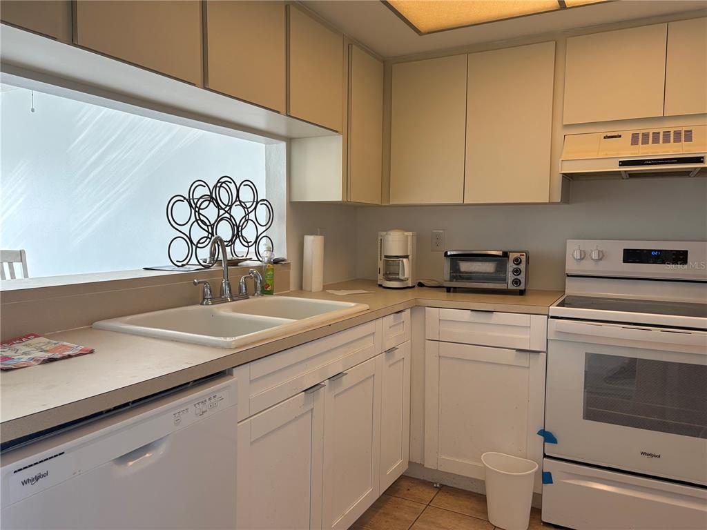 5157 Silent Loop, Unit 115 New Port Richey, FL 34652 - Photo 4 of 18 a kitchen with white cabinets and white appliances
