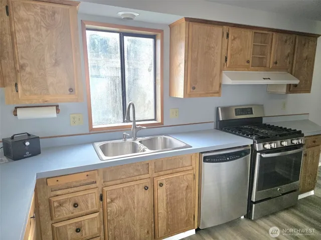 a kitchen with cabinets appliances a sink and a window