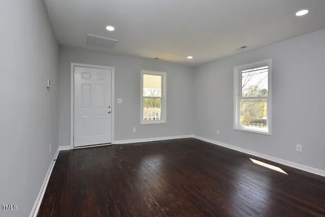an empty room with wooden floor and windows