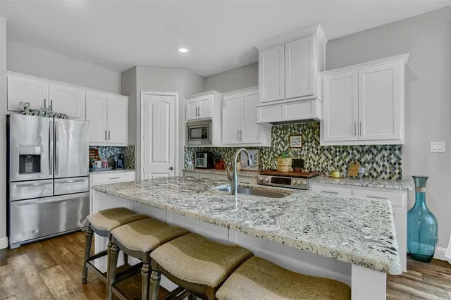 a kitchen with stainless steel appliances granite countertop a stove refrigerator sink and cabinets