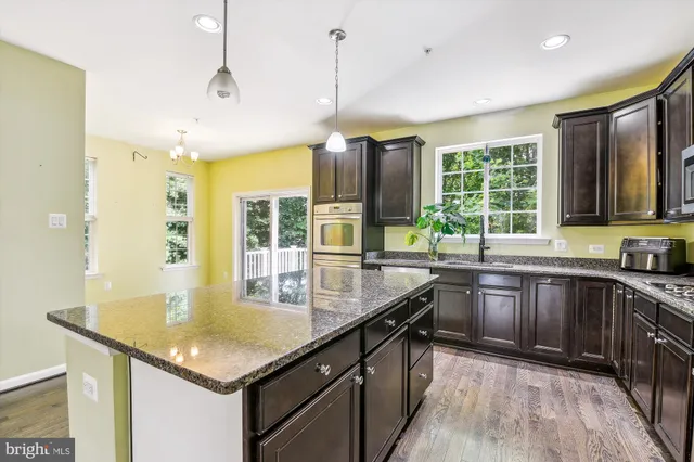 a kitchen with granite countertop cabinets a sink a window and stainless steel appliances