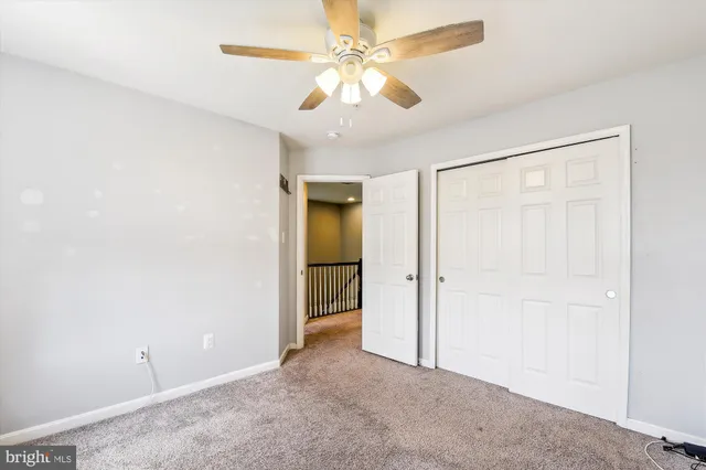 an empty room with closet and a chandelier fan