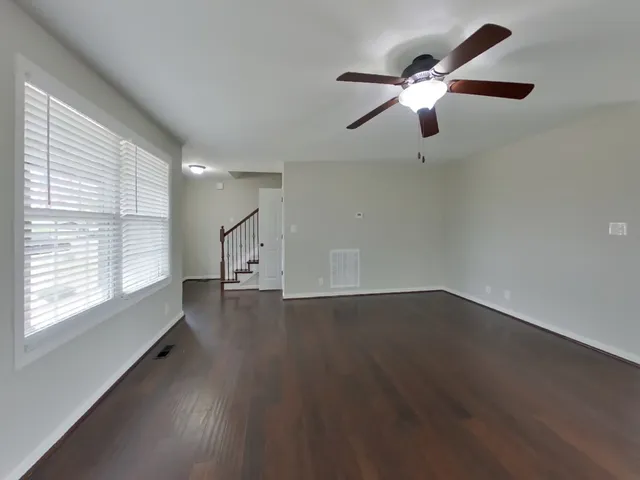 an empty room with wooden floor fan and windows