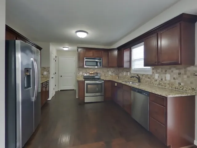 a kitchen with stainless steel appliances granite countertop a refrigerator a stove a sink and a microwave