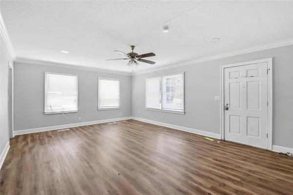 a view of an empty room with wooden floor and a window