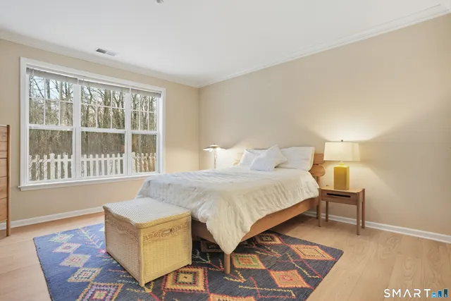 a spacious bedroom with a bed and wooden floor