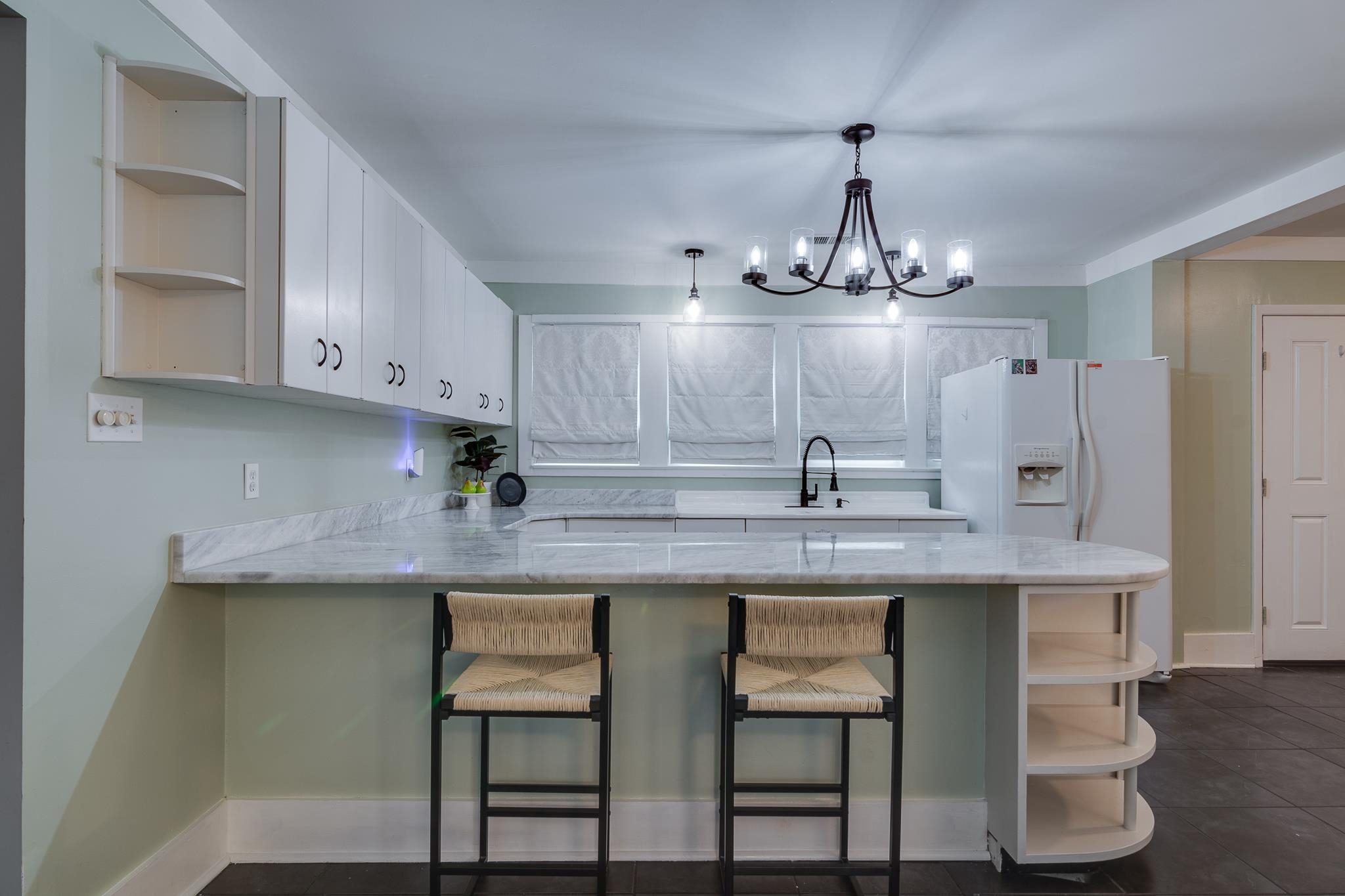 524 Alexander Street Memphis, TN 38111 - Photo 12 of 34 Kitchen featuring a notable chandelier, white cabinetry, kitchen peninsula, light stone counters, and a breakfast bar