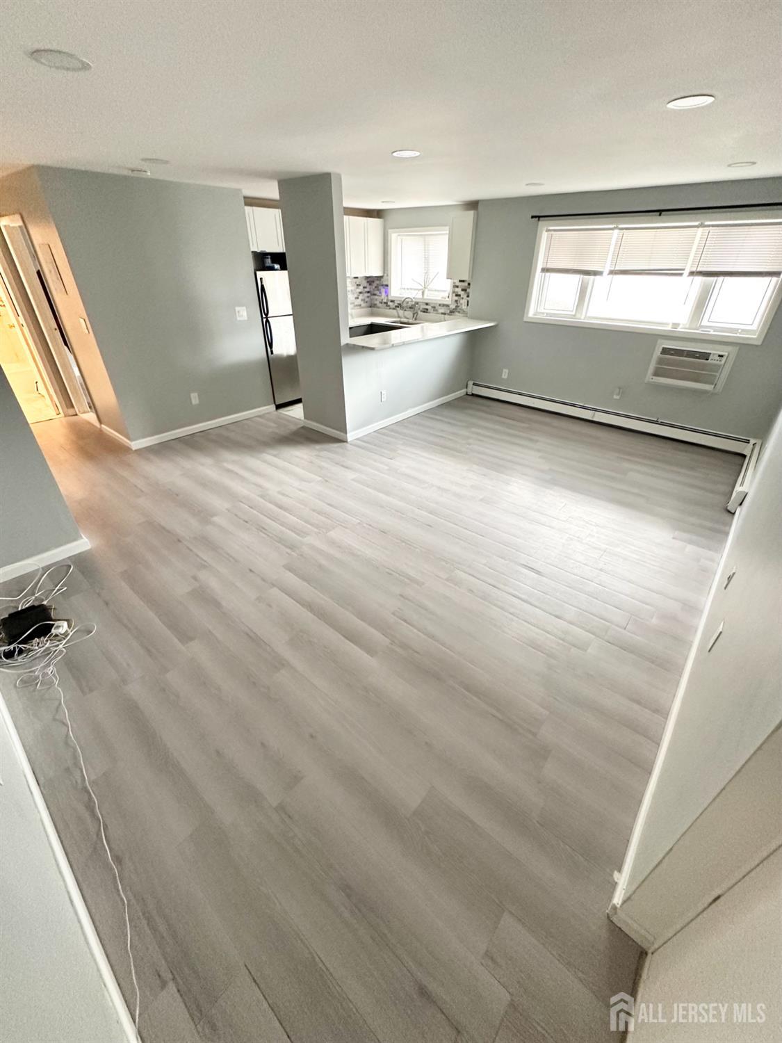 a view of a big room with wooden floor and windows