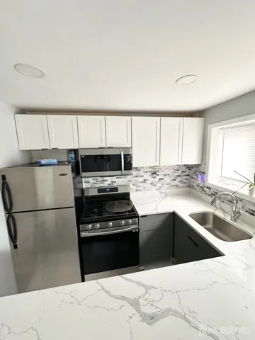 a kitchen with stainless steel appliances granite countertop a refrigerator a sink and a stove