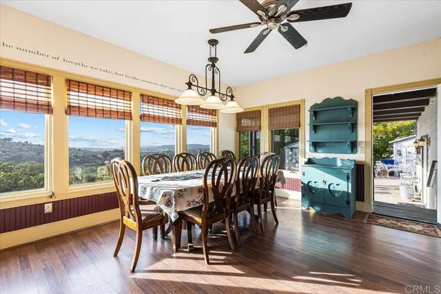 a dining room with wooden floor a chandelier a wooden table and chairs