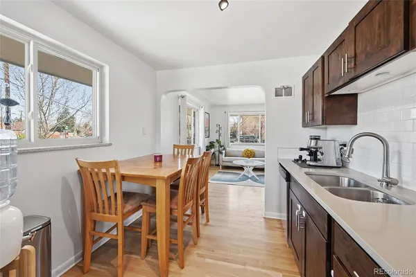 a kitchen with stainless steel appliances granite countertop a stove top oven a sink a dining table and chairs