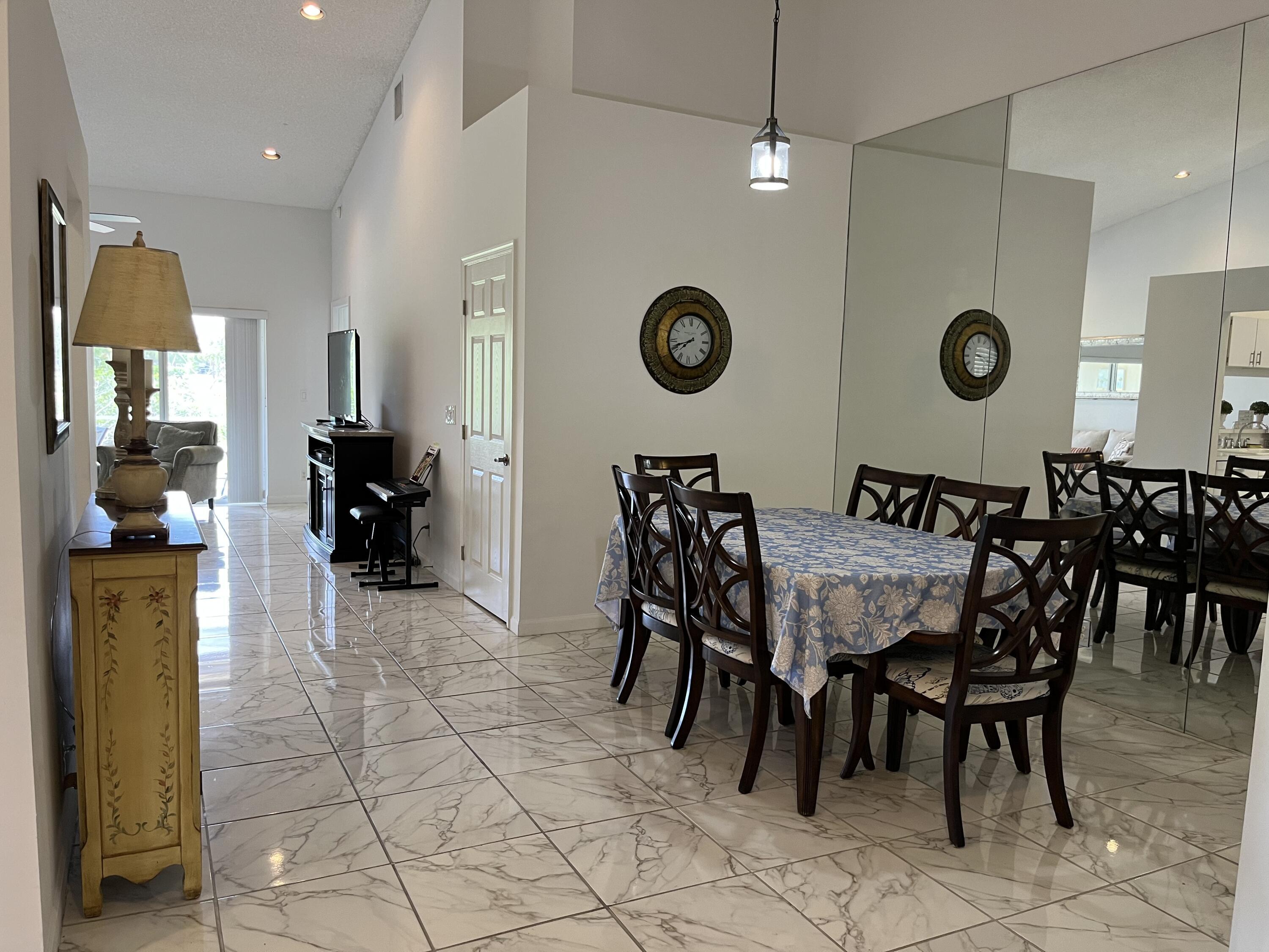 21105 Vía Solano Boca Raton, FL 33433 - Photo 5 of 14 a dining room with granite countertop a table chairs and a clock on the wall