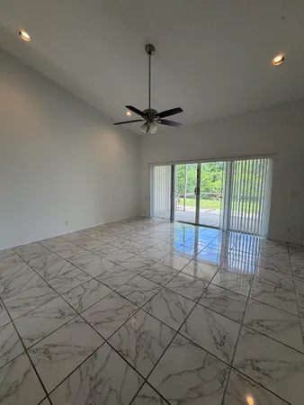 a view of a room with a ceiling fan and carpet