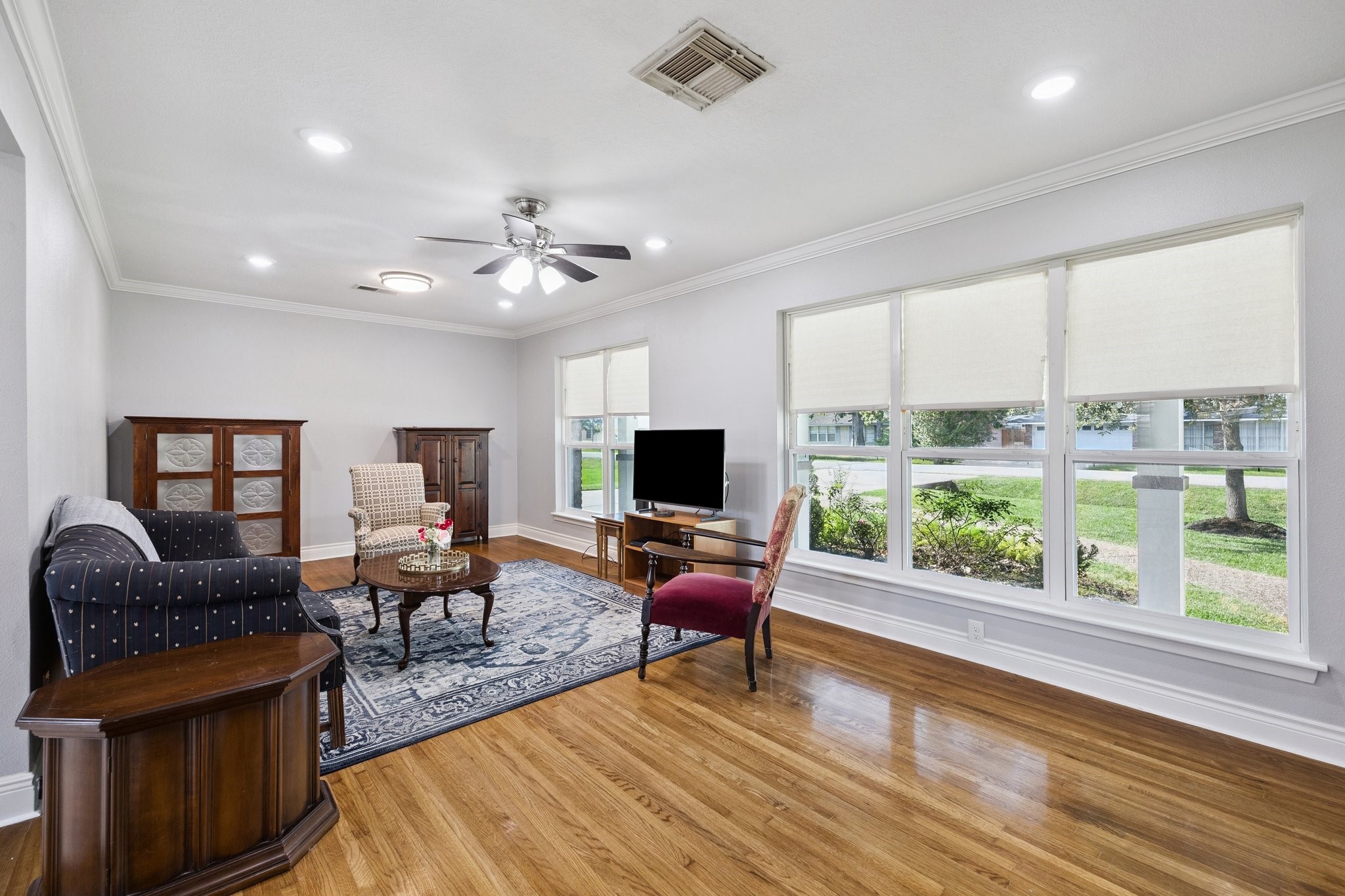 8911 Blankenship Drive Houston, TX 77080 - Photo 2 of 21 This inviting living room offers an abundance of natural light thanks to its large windows, complemented by beautiful hardwood floors and soft recessed lighting. The cozy seating area invites relaxation, and the ceiling fan adds a touch of comfort, creating a warm and welcoming atmosphere perfect for both entertaining guests and enjoying quiet evenings at home.