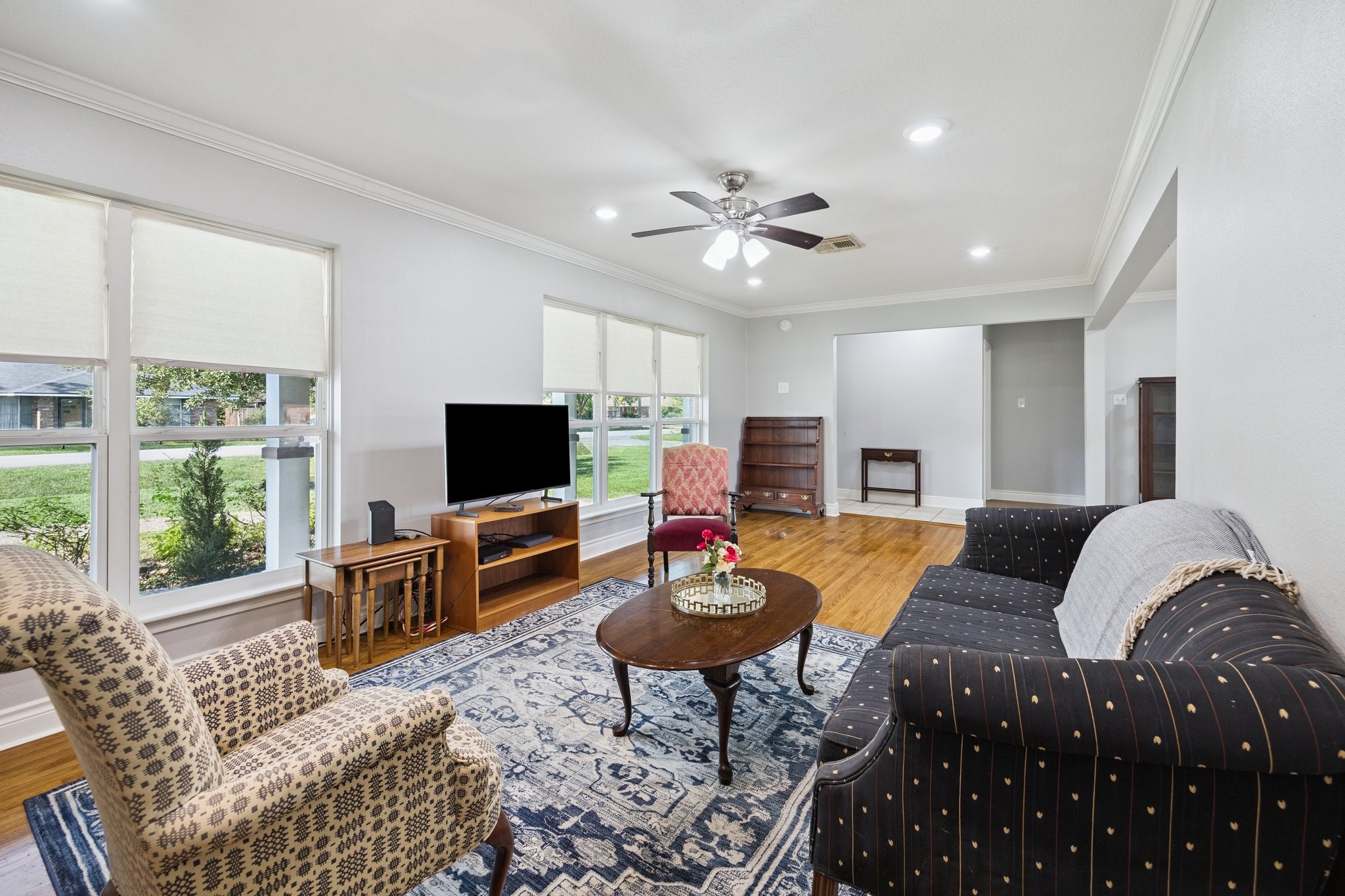 8911 Blankenship Drive Houston, TX 77080 - Photo 3 of 21 Bright and inviting living room with large windows offering plenty of natural light. Features include hardwood floors, a ceiling fan, and ample space for seating. Perfect for relaxation and entertaining.