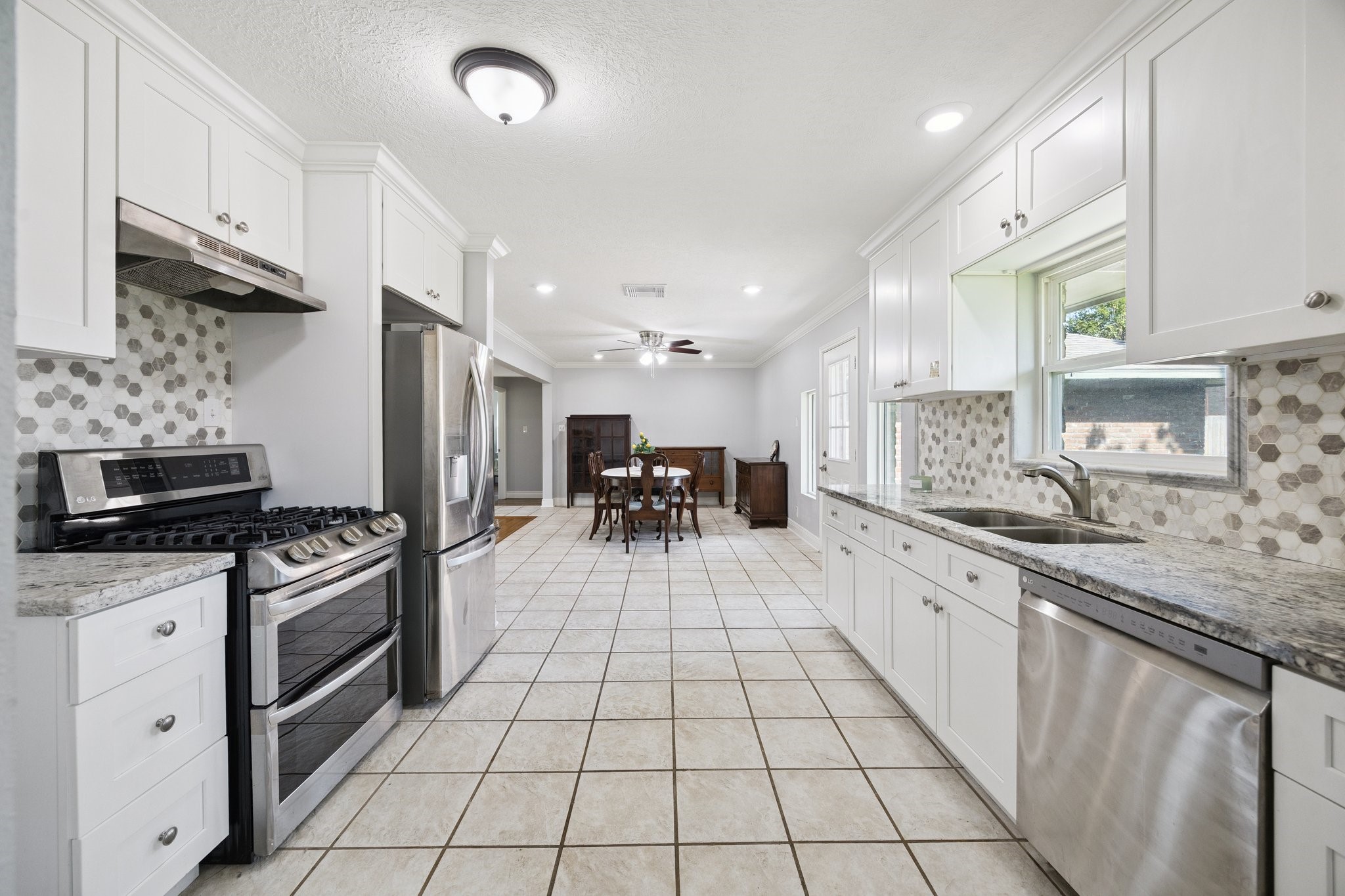 8911 Blankenship Drive Houston, TX 77080 - Photo 8 of 21 This inviting kitchen boasts modern stainless steel appliances and elegant granite countertops, designed for both style and functionality. With soft-close drawers and stunning white cabinetry paired with a chic hexagonal tile backsplash, it’s a chef’s dream. The seamless flow into the cozy dining area creates a bright, welcoming atmosphere, ideal for memorable family gatherings and entertaining guests.