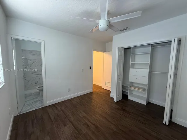an empty room with wooden floor closet and windows
