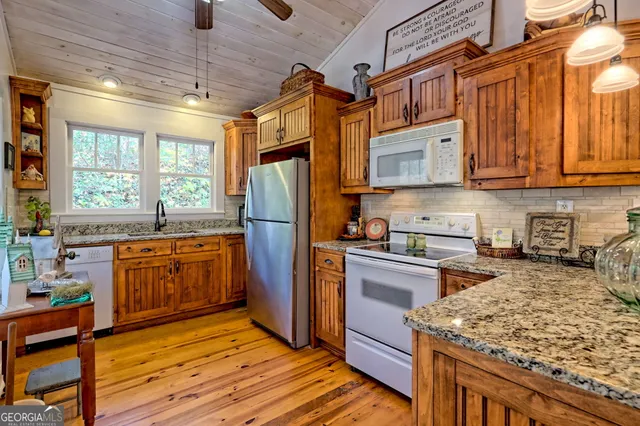 a kitchen with stainless steel appliances granite countertop a stove a refrigerator a sink dishwasher a oven and wooden cabinets with wooden floor