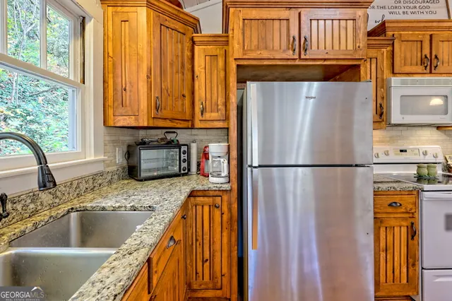 a kitchen with granite countertop a refrigerator and a sink