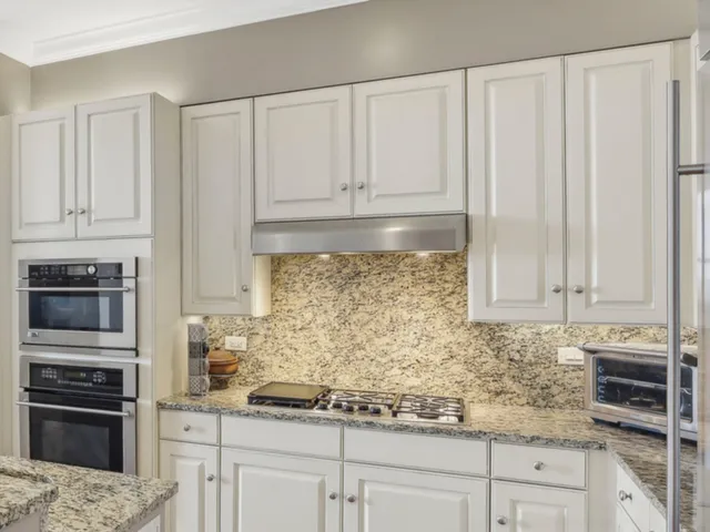 a kitchen with granite countertop white cabinets and stainless steel appliances