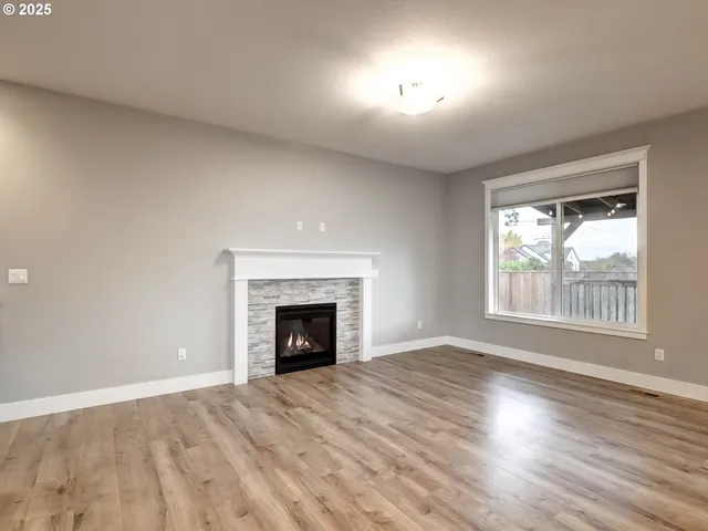 an empty room with wooden floor fireplace and windows