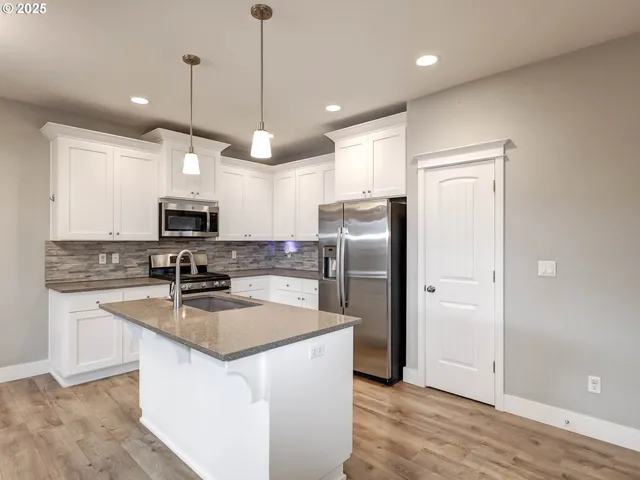 a kitchen with stainless steel appliances granite countertop a refrigerator a sink a stove and oven