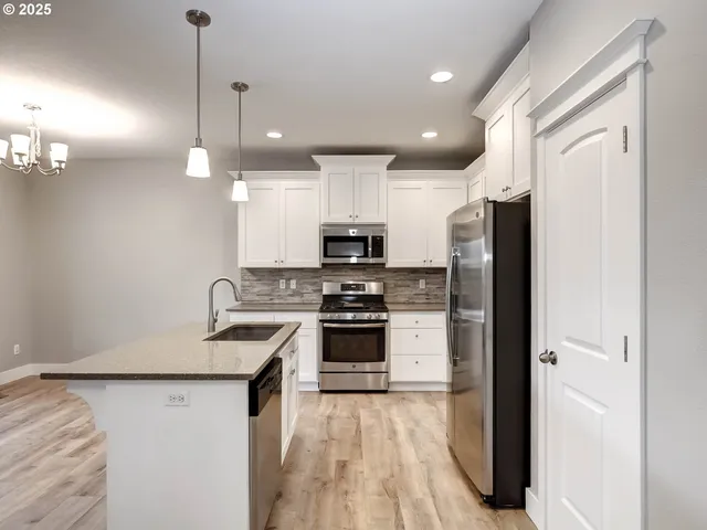 a kitchen with kitchen island a counter space a sink appliances and cabinets