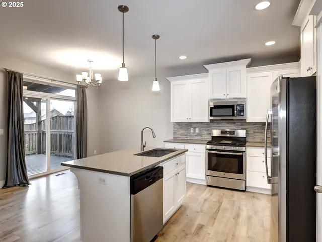 a kitchen with stainless steel appliances granite countertop a sink a stove a refrigerator and a microwave