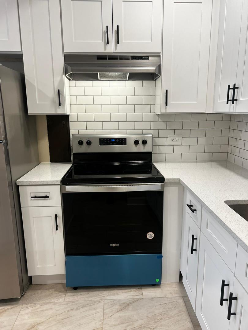 10102 Main Street, Unit 1A Hebron, IL 60034 - Photo 15 of 18 a kitchen with a stove and white cabinets