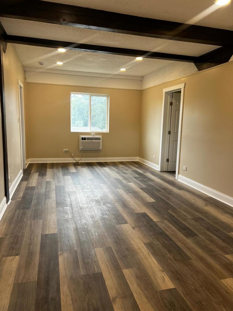 10102 Main Street, Unit 1A Hebron, IL 60034 - Photo 6 of 18 a view of an empty room with wooden floor and a window