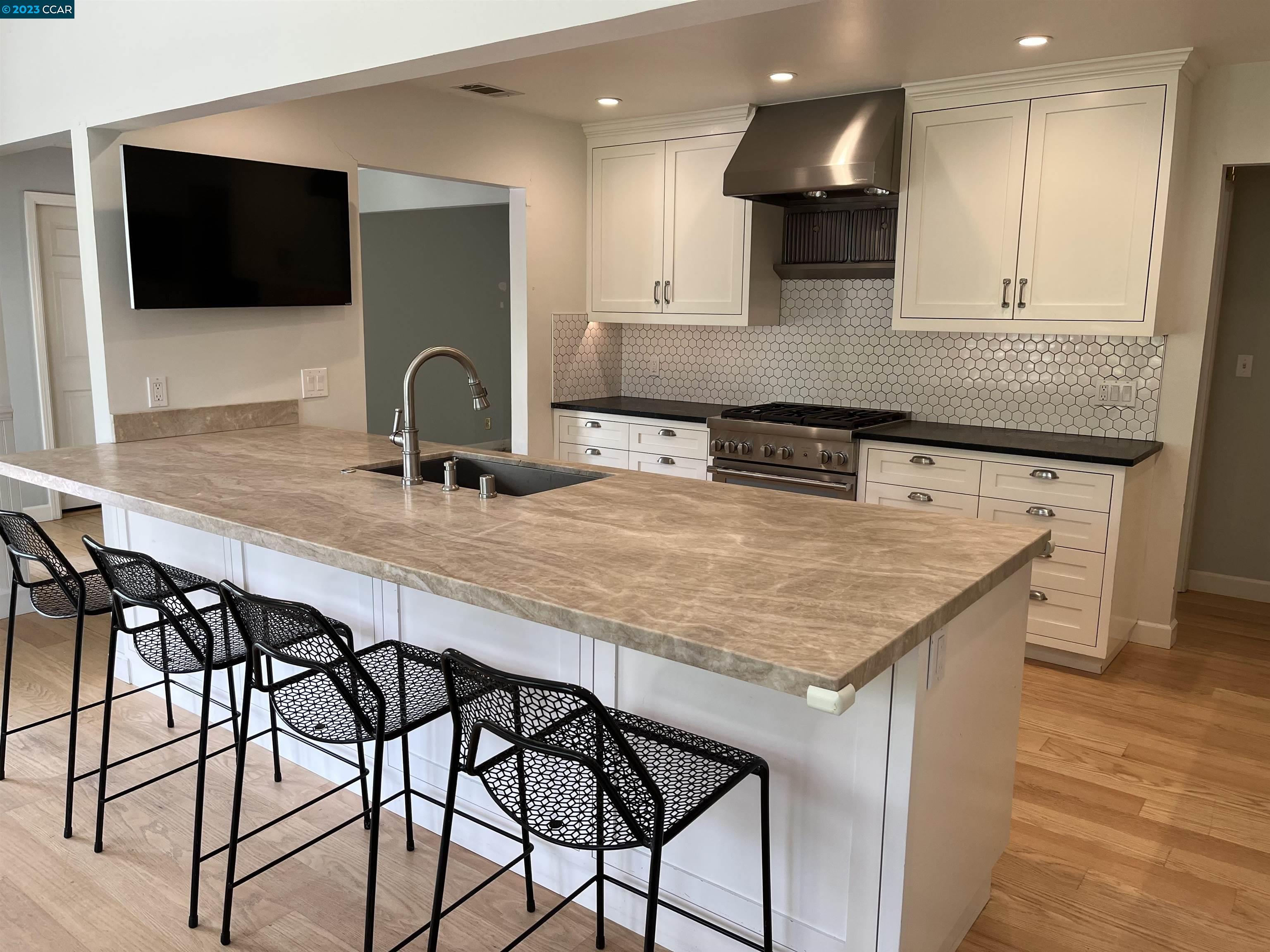 3524 Oliver Court Lafayette, CA 94549 - Photo 5 of 32 a kitchen with stainless steel appliances kitchen island a table chairs in it and wooden floors