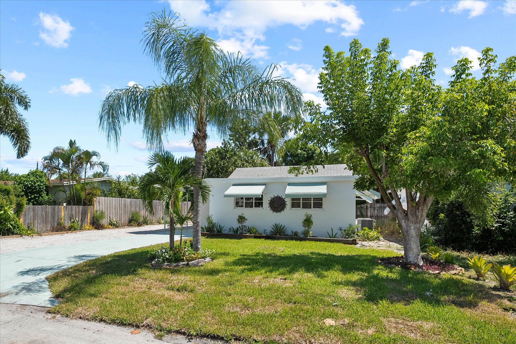 7936 Terrace Road Lantana, FL 33462 - Photo 2 of 25 a view of a white house with a yard and palm trees