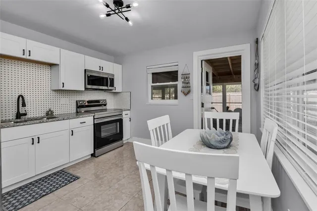 a kitchen with stainless steel appliances kitchen island granite countertop a sink a stove a microwave oven a dining table and chairs with wooden floor