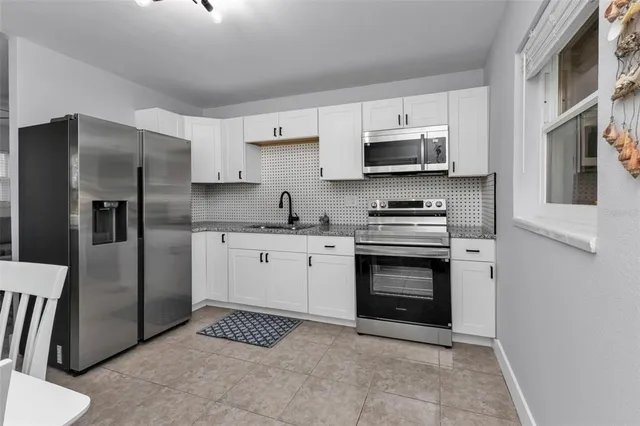 a kitchen with stainless steel appliances granite countertop a refrigerator stove and sink