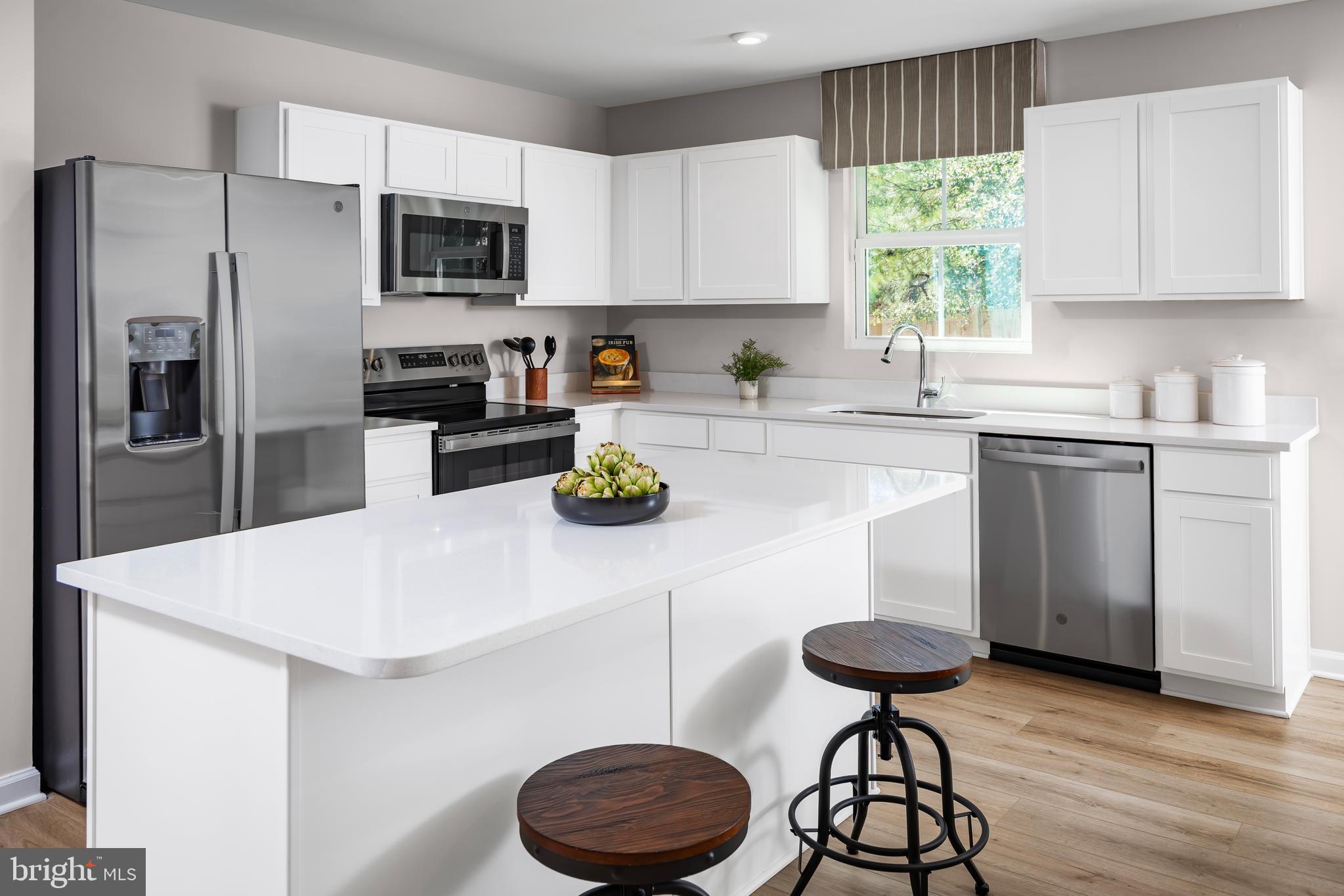 4408 Mutual Drive Inwood, WV 25428 - Photo 4 of 15 a kitchen with a refrigerator a stove a sink and white cabinets with wooden floor