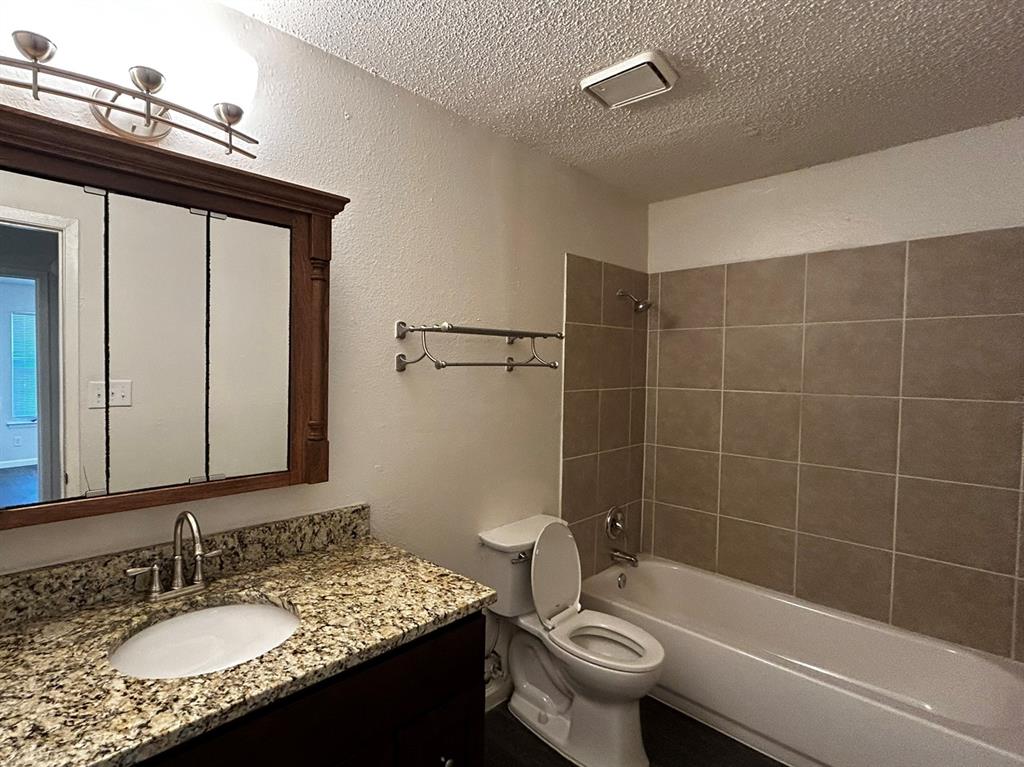2200 East Trinity Mills Road, Unit 301 Carrollton, TX 75006 - Photo 11 of 16 a bathroom with a granite countertop sink a toilet a mirror and shower