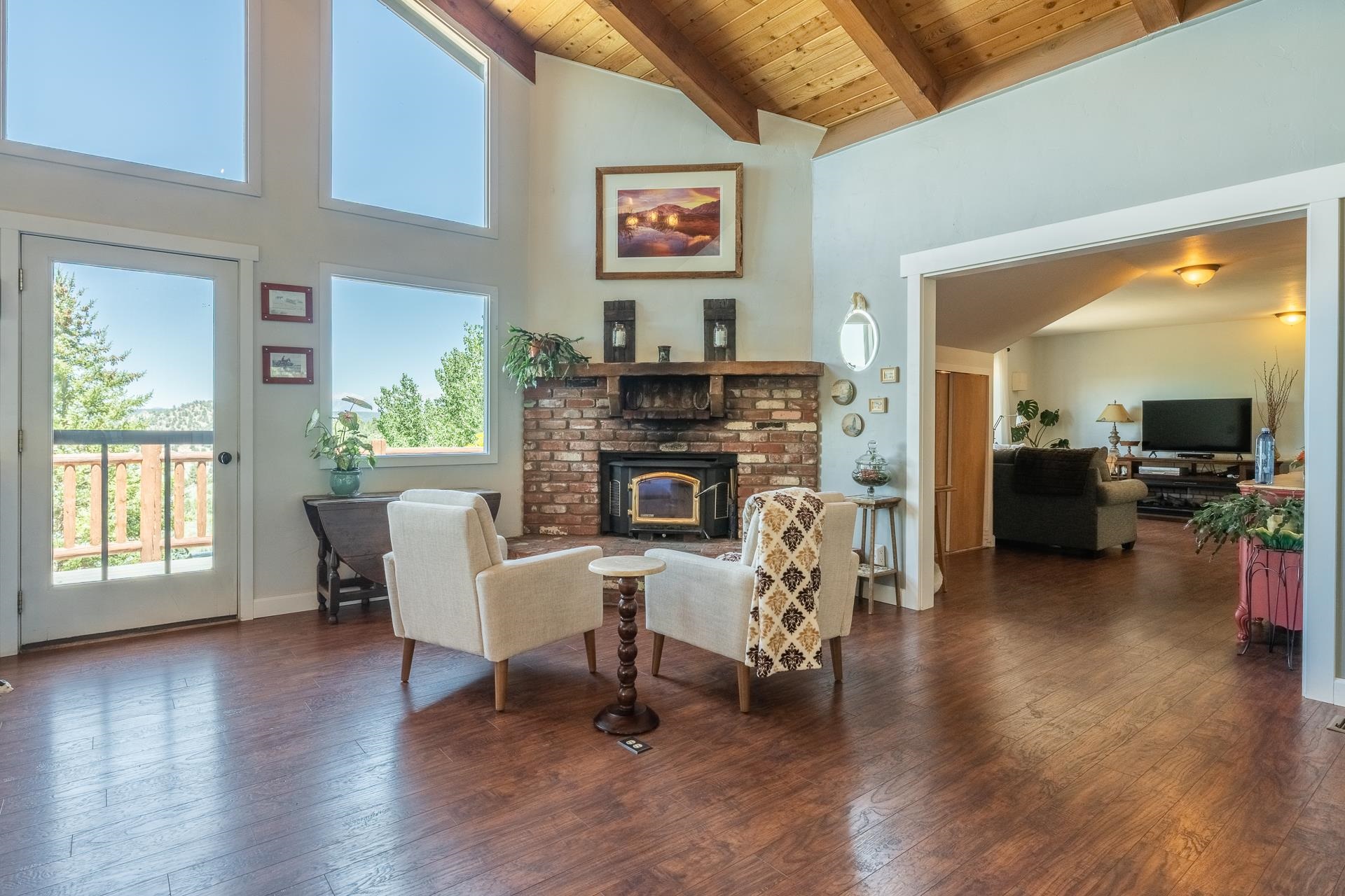 537 Aspen Spring Ranch Road Mammoth Lakes, CA 93546 - Photo 9 of 40 Vaulted ceiling with exposed wood beams, brick fireplace with insert, wood-finish flooring, and multiple windows offering expansive outdoor scenery