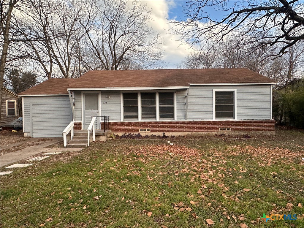 a front view of house with yard and trees around