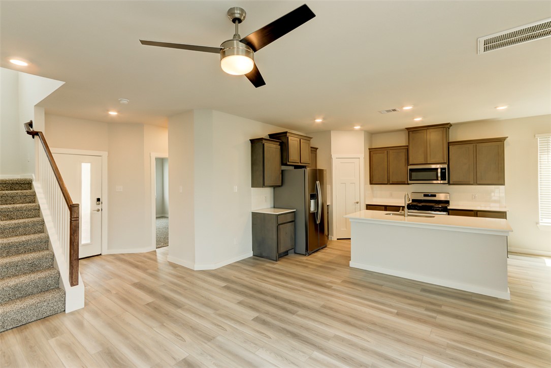 760 Double Mountain Road College Station, TX 77845 - Photo 5 of 26 a kitchen with stainless steel appliances kitchen island granite countertop a refrigerator a stove top oven a sink dishwasher and white cabinets with wooden floor